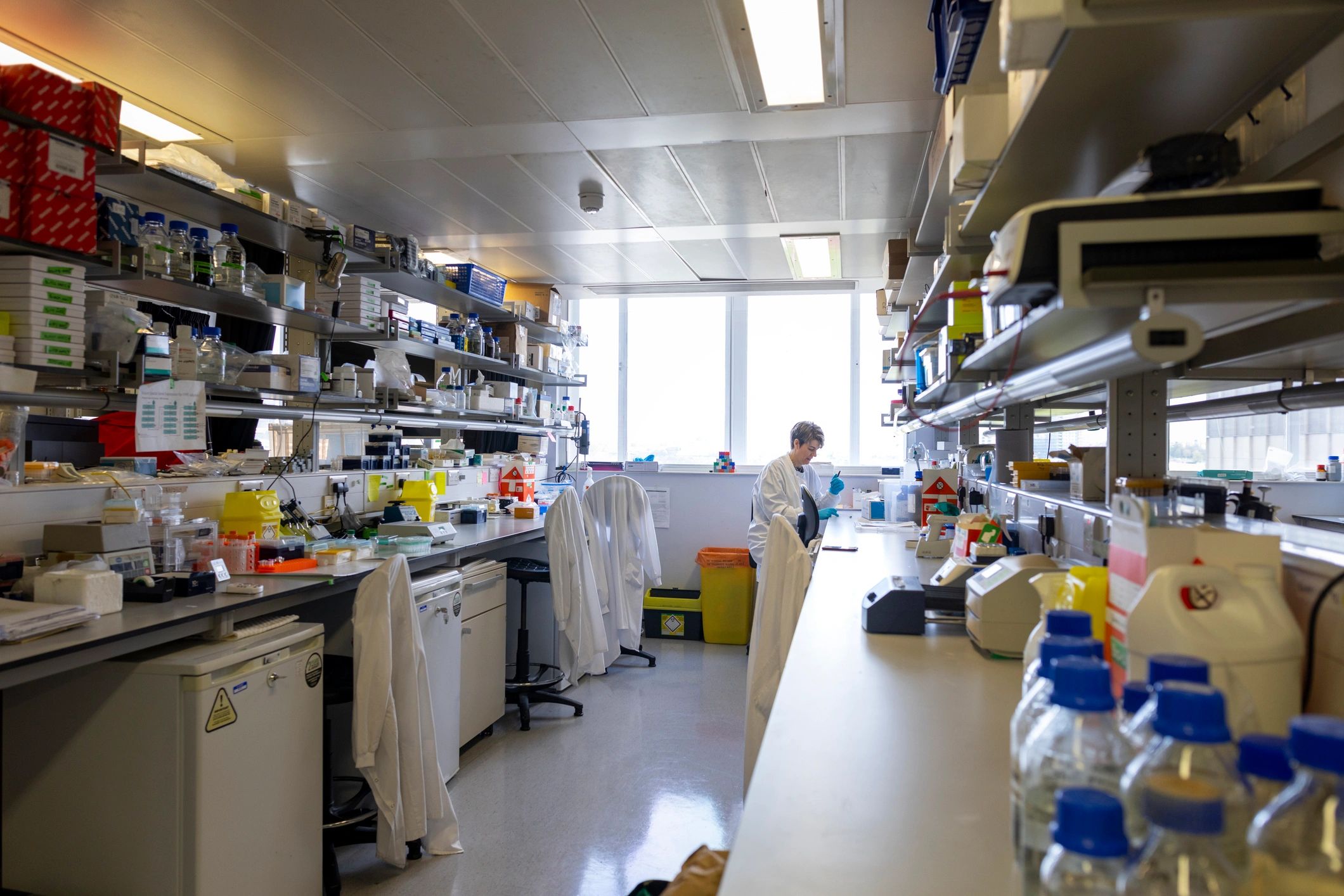 Researcher in a lab coat working with lab equipment